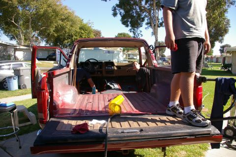 1986 Ford Bronco - A red pickup truck is being worked on in a residential driveway.