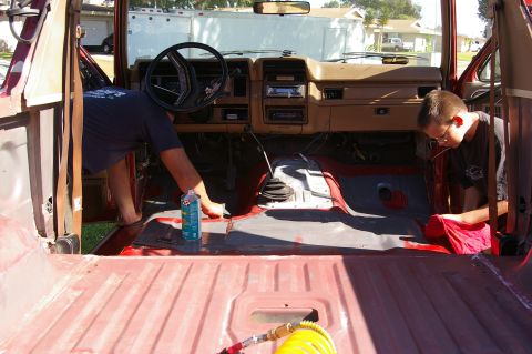 1986 Ford Bronco - Two individuals are cleaning the interior of a 1986 Ford Bronco, preparing it for a Herculiner application.