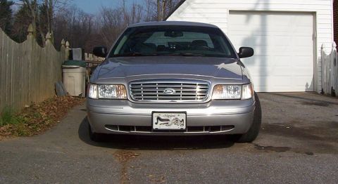 2004 Ford Crown Victoria - A silver 2004 Ford Crown Victoria is parked in front of a garage door.