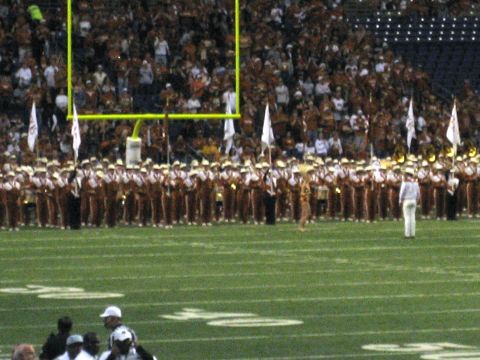 1986 Ford Bronco - A marching band lines up on a football field in front of a crowd and goal post.