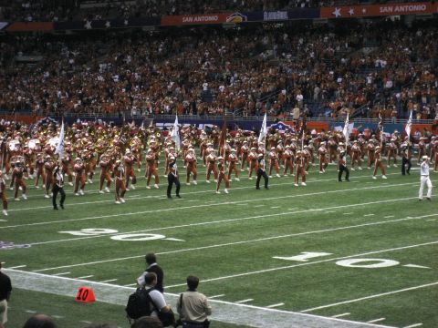 1986 Ford Bronco - A marching band performs on a football field during an event, with a large crowd in the background.