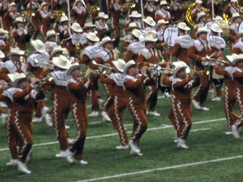 1986 Ford Bronco - A marching band performs on a football field, with members wearing cowboy hats and brown and white uniforms.