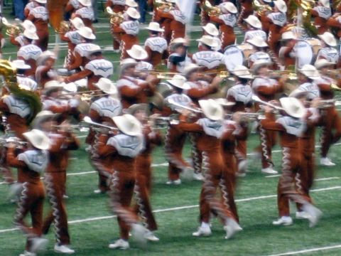 1986 Ford Bronco - A marching band performs on a green field, wearing distinctive uniforms and cowboy hats.