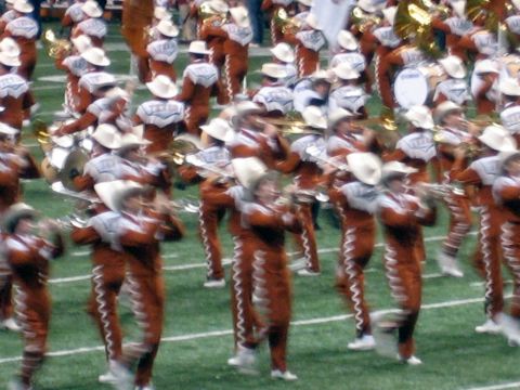 1986 Ford Bronco - A marching band performs on a football field, with members in distinctive orange and white uniforms.