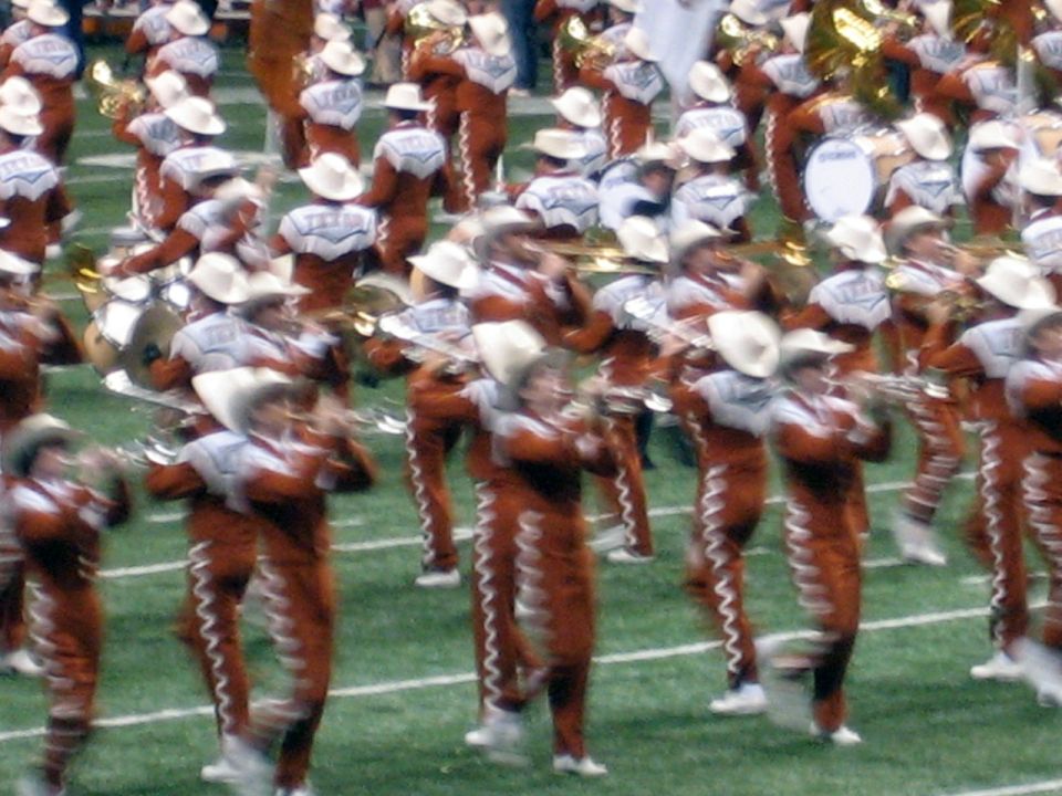 Marching band in orange and white uniforms on a green field