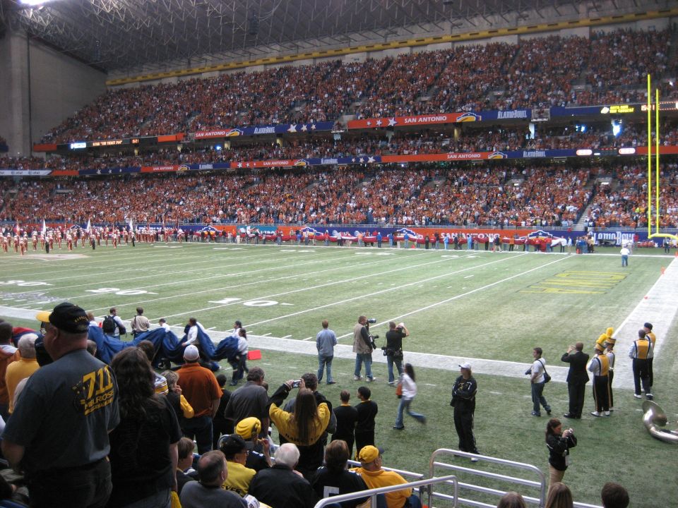 Crowded football stadium with orange-clad spectators and a marching band on the field