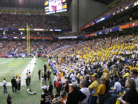 1986 Ford Bronco - A football game is underway in a packed stadium, with fans in the stands and a band on the field.