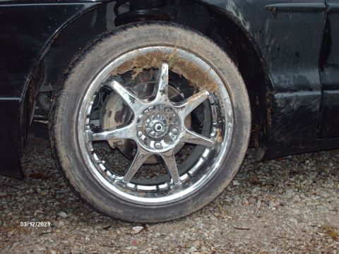 1995 Ford Probe - A close-up view of a dirty wheel and tire on a black vehicle, showing debris stuck to the rim.