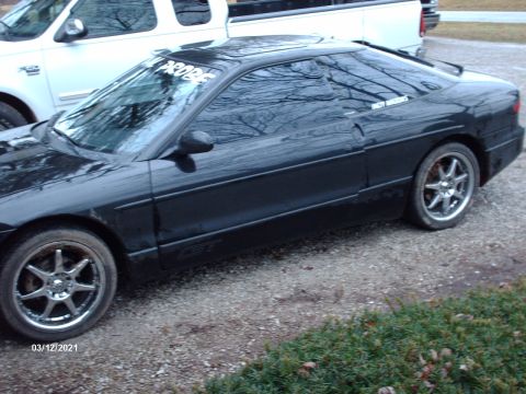 1995 Ford Probe - A black Ford Probe is parked next to a white pickup truck.