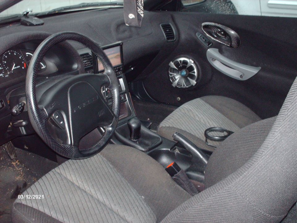 Interior view of a 1995 Ford Probe showing the dashboard, steering wheel, seats, and door panel