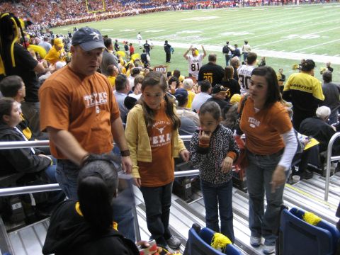 1986 Ford Bronco - Fans dressed in team colors occupy stadium seating during a football game.