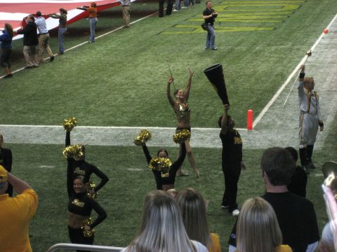 1986 Ford Bronco - A football game scene with cheerleaders and a large flag being held by attendees.