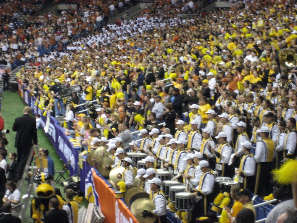 Crowd in stadium with marching band playing drums and cymbals