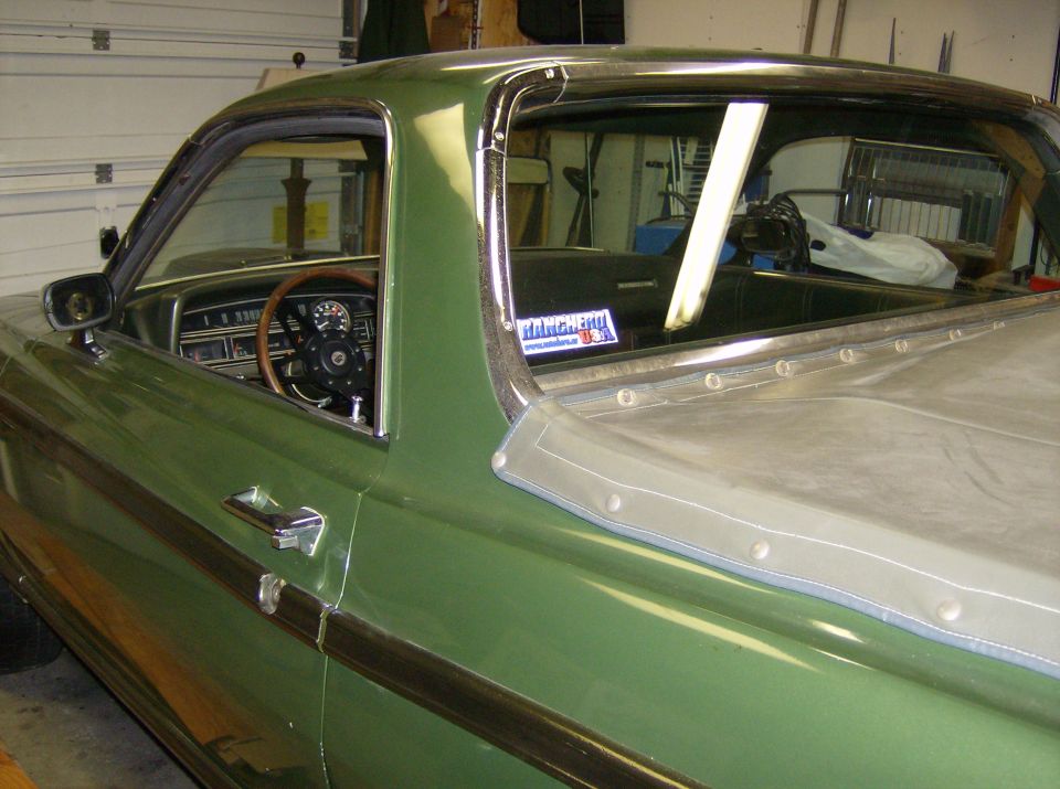 Green Ford Ranchero cab close-up in garage with wood steering wheel and riveted bed cover