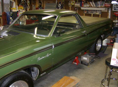 1970 Ford Ranchero - A green 1970 Ford Ranchero is shown from the side, elevated on jack stands inside a workshop.