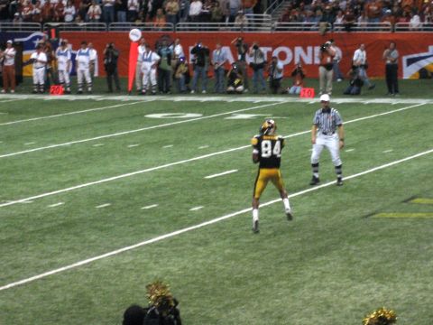 1986 Ford Bronco - A football player in a yellow and black uniform stands on the field during a game, with a referee watching.