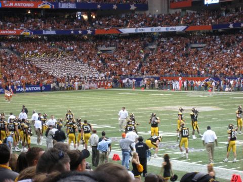 1986 Ford Bronco - A football game is underway in a crowded stadium, with players on the field and spectators in the stands.