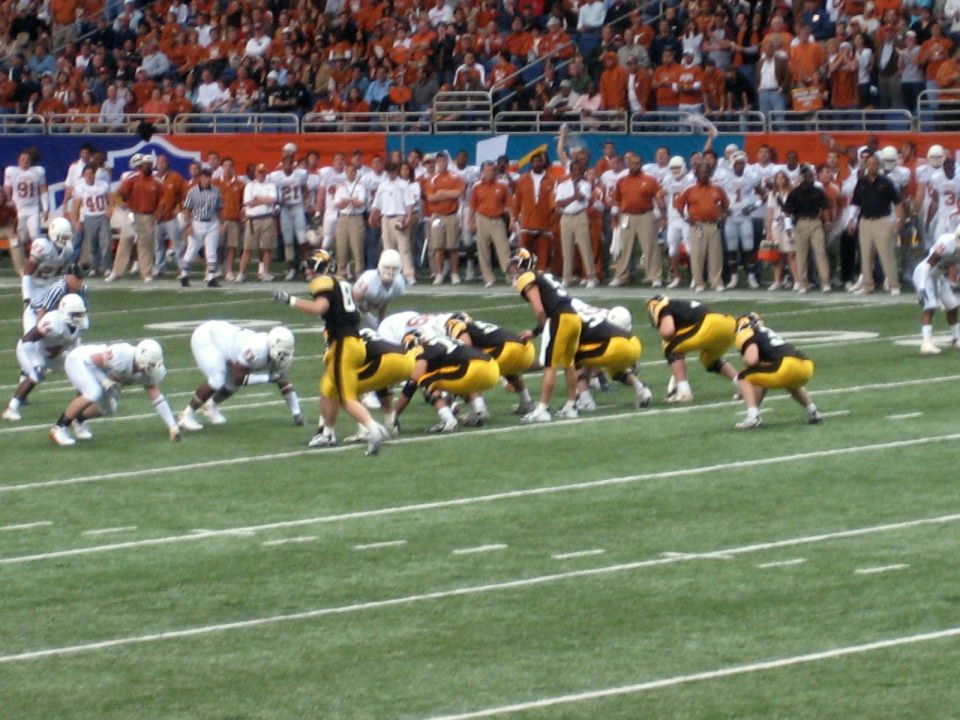 football players in yellow and white uniforms on a field, crowd in background