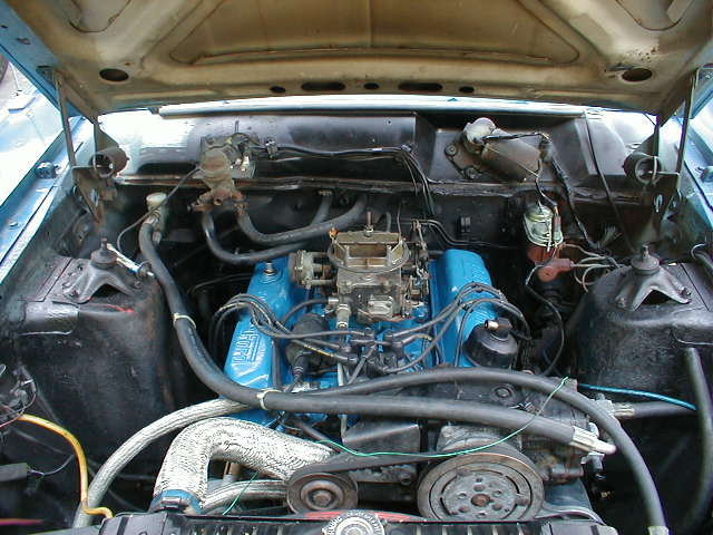 Blue V8 engine bay with four-barrel carburetor and hoses under raised hood