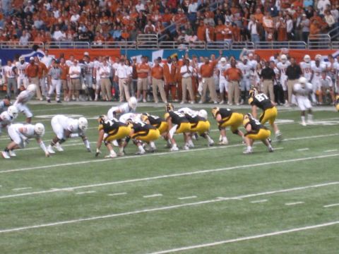 1986 Ford Bronco - Players line up on the field during an American football game, with a crowd watching from the stands.