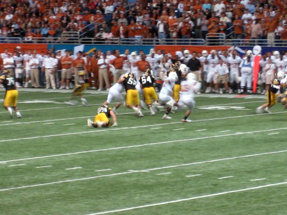 football players in action on a field during a game, with spectators in the background