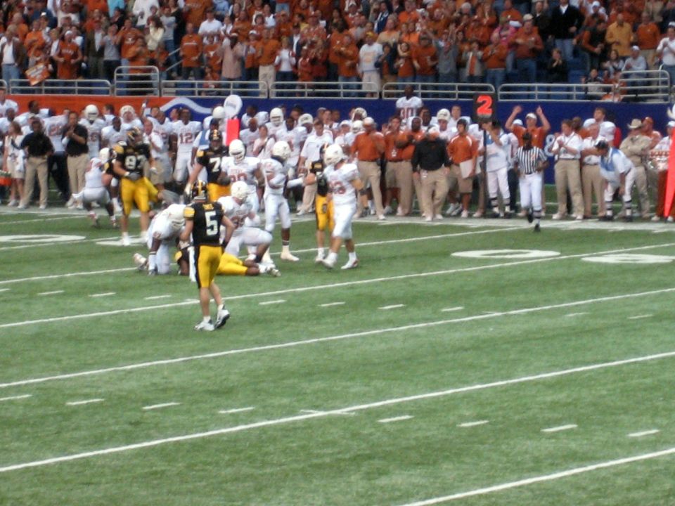 Football players on a field during a game, with spectators in the background