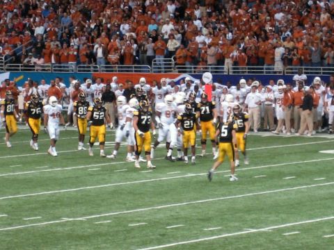 1986 Ford Bronco - Players enter the field during a football game, with a large crowd watching from the stands.