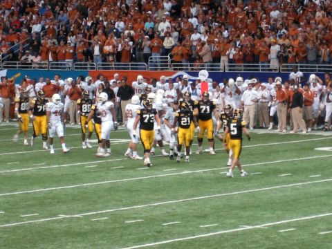 1986 Ford Bronco - Players in uniform are on the field during a football game, with spectators in the stands.