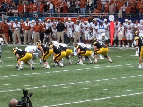 1986 Ford Bronco - A football game is underway with players lined up on the field and spectators in the stands.