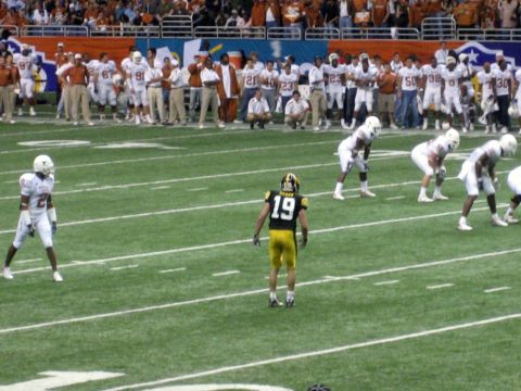 1986 Ford Bronco - Players from two teams face off on a football field, with spectators in the background.