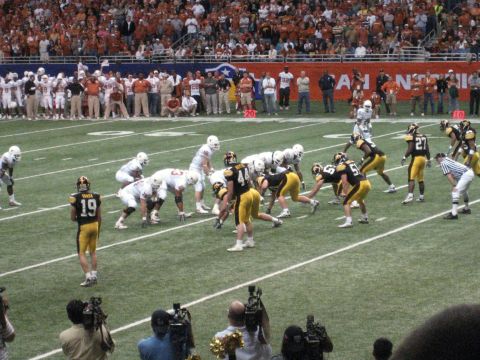 1986 Ford Bronco - A football game is underway with players on the field and spectators in the stands.