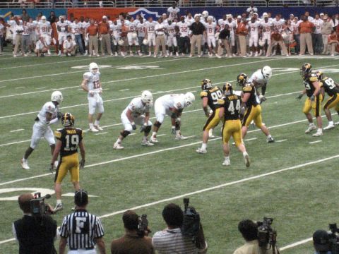 1986 Ford Bronco - A football game is underway with players on the field and spectators watching.