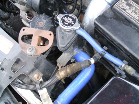 1997 Ford Probe - Close-up view of engine bay components including blue hoses and a coolant reservoir cap. The registry claims this is a 1997 Ford Probe.