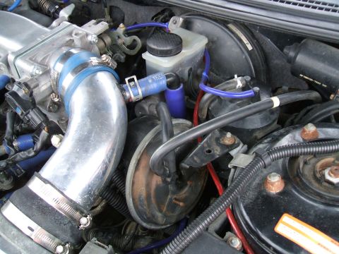 1997 Ford Probe - Close-up view of an engine bay, chrome intake piping, blue hoses, and the brake fluid reservoir.