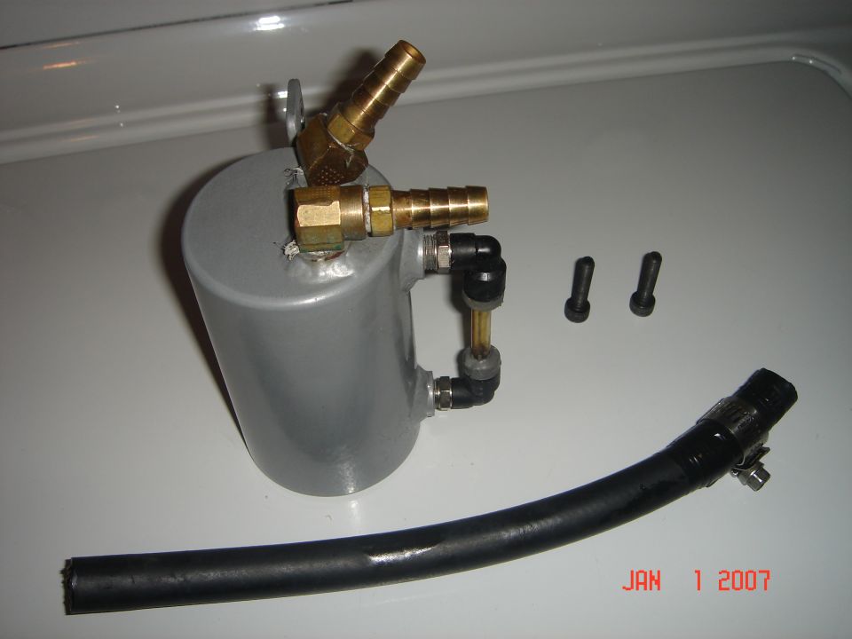 Oil catch can assembly with brass fittings, black hose, and two bolts. Watermark reads JAN 1 2007 SUPERMOTORS.NET