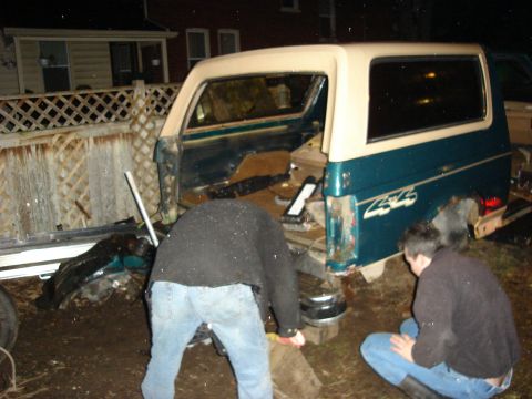1990 Ford Bronco - Teal and cream SUV with 4x4 decal is partially disassembled in a yard.