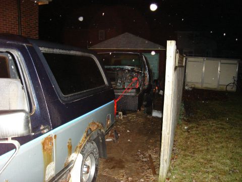 1990 Ford Bronco - Two SUVs are parked in a yard at night, with one vehicle's engine exposed and the other showing significant rust.