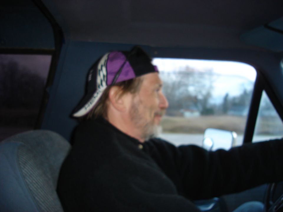 Man wearing a baseball cap driving. Supermotors.net watermark visible