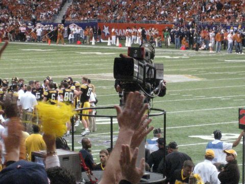 1986 Ford Bronco - A football game is underway with players on the field and a camera crew capturing the action.