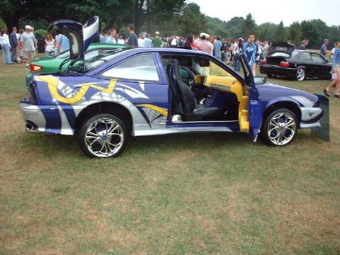 1997 Ford Crown Victoria - A customized blue coupe with unique graphics and doors is displayed outdoors with other vehicles and spectators.