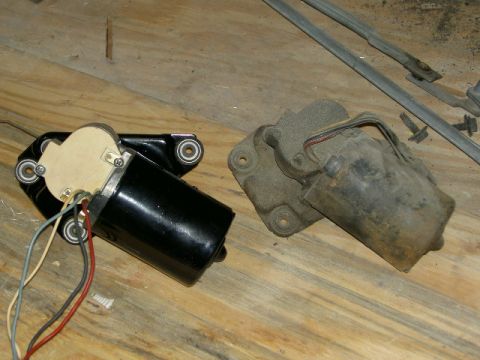 1967 Ford Ranchero - Two windshield wiper motors are shown on a wooden surface. One appears to be a replacement part, while the other is older and corroded.