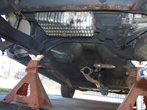 1992 Ford Taurus - The underside of a car is visible, supported by jack stands, with a focus on the exhaust and transmission components.