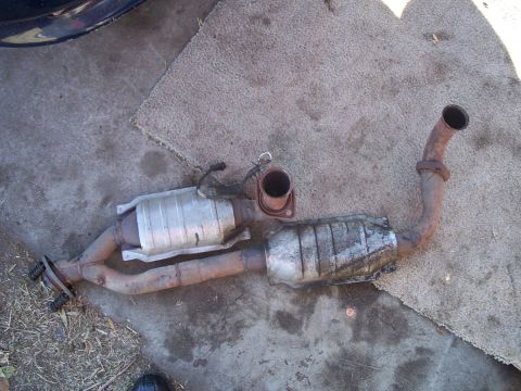 1992 Ford Taurus - A removed exhaust system, two catalytic converters and associated piping, lies on the ground.