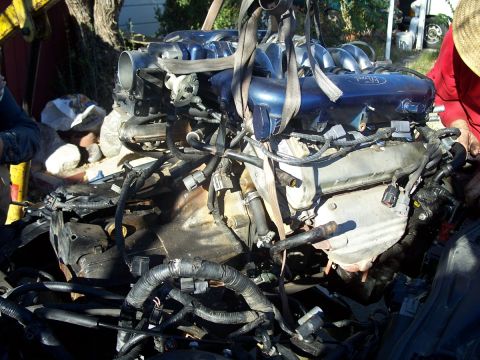 1992 Ford Taurus - A Ford engine, likely removed from a vehicle, is suspended by straps, showing complex wiring and plumbing.