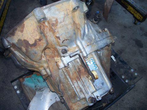1992 Ford Taurus - A heavily corroded transmission part sits on a metal stand in a workshop.