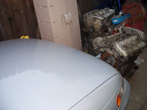 1992 Ford Taurus - Two V6 engines are stored in a garage next to a car.