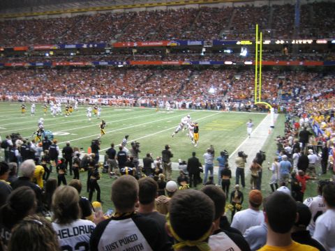 1986 Ford Bronco - A football game is underway in a crowded stadium, with players on the field and spectators in the stands.