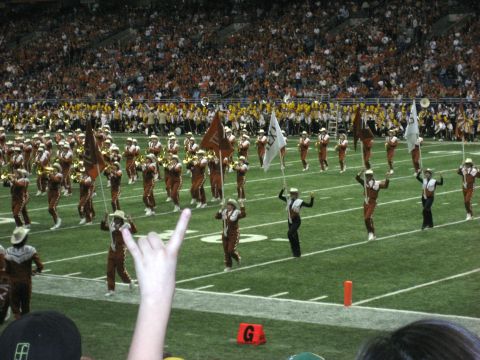 1986 Ford Bronco - A marching band performs on a football field during a game, with a large crowd in the background.
