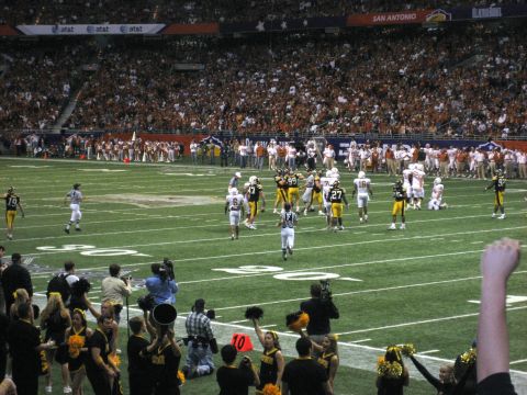 1986 Ford Bronco - A football game is underway with players on the field and a large crowd in the stadium stands.