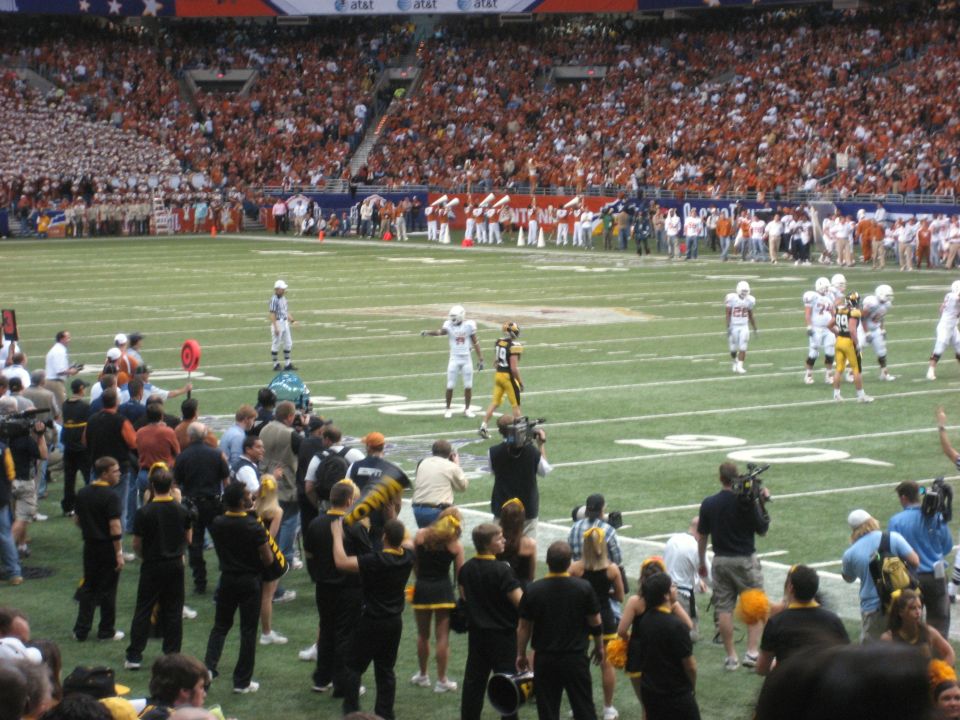 Football players on a field with a large crowd in the stands
